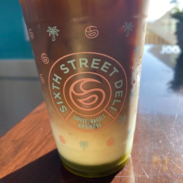 Iced coffee with a green layer at the bottom, in a 6th Street Deli branded cup.